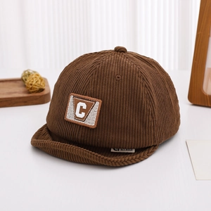 Close-up of brown corduroy baby cap with C letter embroidery and soft turned-up brim