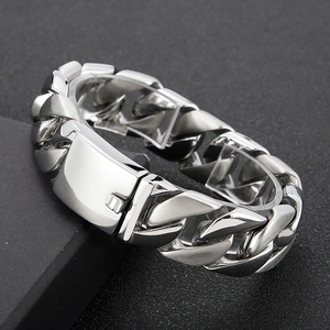 Macro shot of silver Cuban link bracelet featuring a square buckle on dark textured surface