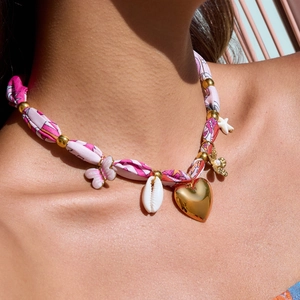 Close-up of bohemian silk ribbon necklace with golden heart, bee, and butterfly charms