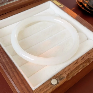 Detailed view of polished white jade-like bangle in a luxury wooden gift box