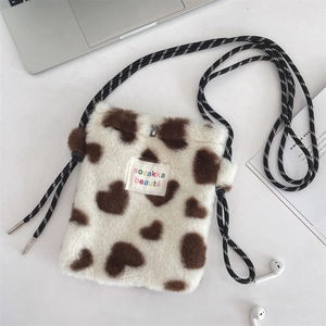 Gros plan détaillé du mini sac en peluche blanc avec motifs cœurs et bandoulière