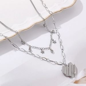 Détail du collier double couche argenté avec pendentifs étoile et cœur sur céramique
