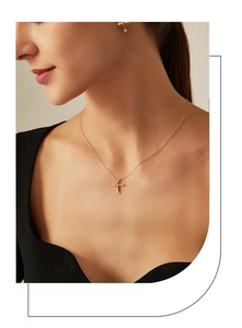 Close-up of elegant gold cross necklace and earrings with zircon on female model
