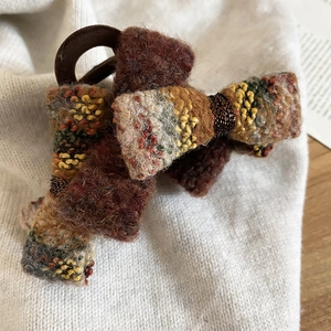 Detailed macro view of coffee and green knitted velvet bow hair tie with soft texture