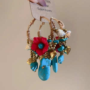 Detail of ethnic hoop earring with woven rope, turquoise stones, and red flower charms