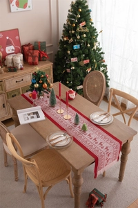 Detail of red Christmas table runner with white reindeer patterns and handmade tassels
