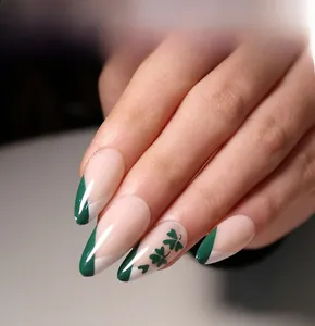 Detail of long almond press-on nails with green French tips and clover heart patterns
