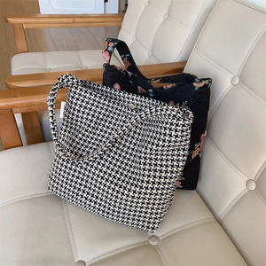 Detail of floral embroidery and houndstooth pattern fabric bags on a vintage chair