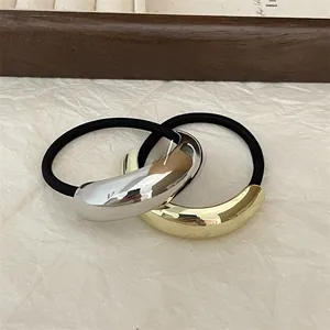 Detail of minimalist gold and silver crescent alloy hair ties with black elastic bands