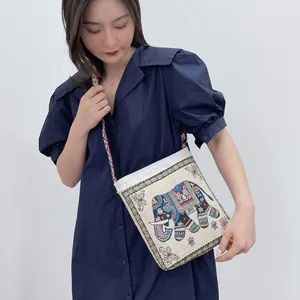 Detail of ethnic canvas crossbody bag with colorful elephant embroidery and braided strap