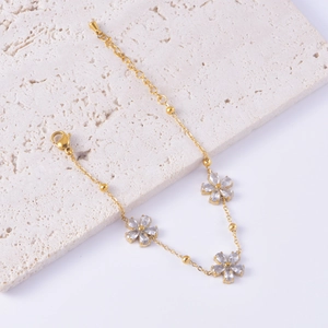 Detailed shot of golden flower bracelet with clear zircons and adjustable lobster clasp