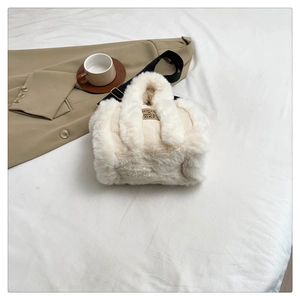 Detail of soft cream plush tote bag with detachable black strap on white fabric