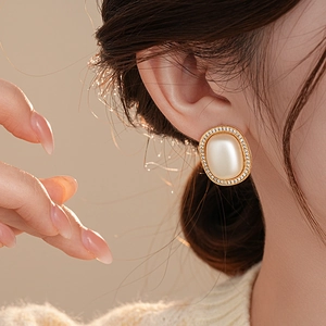Close-up of a model wearing a gold pearl earring with cubic zirconia accents in a side view