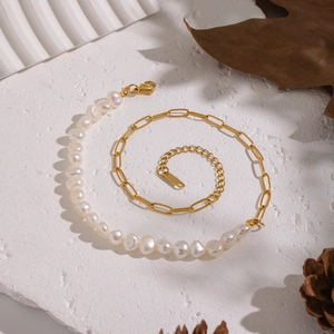 Detail of freshwater pearls and golden paperclip chain necklace on a stone background