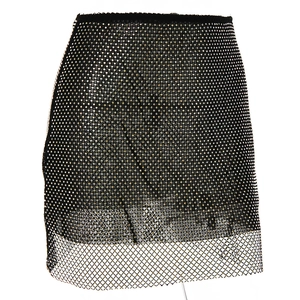 Detailed macro shot of dense gold rhinestones on black mesh fabric mini skirt