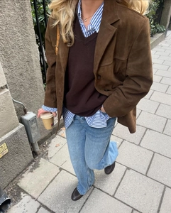 Detailed street style view of vintage brown suede jacket paired with layered autumn knitwear