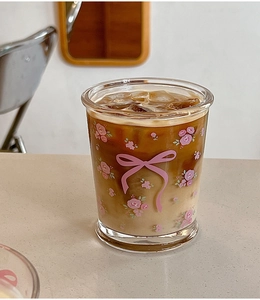 Gros plan d'un verre avec motifs roses et nœuds rempli de latte glacé sur une table