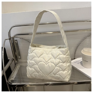 Détails du motif matelassé en cœur et cuir crème brillant sur ce sac fourre-tout chic