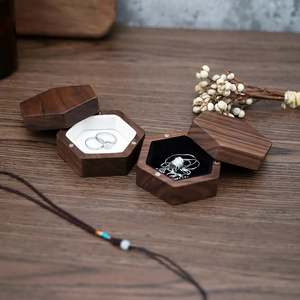 Detail of hexagonal walnut wood jewelry boxes for rings and necklaces on table
