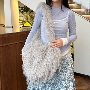 Chic light gray fuzzy plush tote bag with long tassels shown on shoulder by model