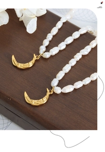 Macro view of baroque pearl necklace with gold textured crescent moon pendants