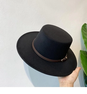 Close-up of black felt fedora hat featuring a brown leather strap and gold metal buckle