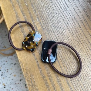 Close-up of amber and black rectangle hair ties with rhinestones on a wood surface