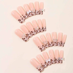Long coffin nude pink press-on nails with leopard print tips and 3D white bow decorations