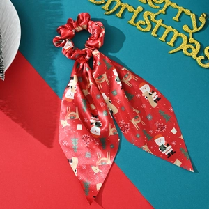Detail of red Christmas satin scrunchie with ribbons featuring festive reindeer and santa prints