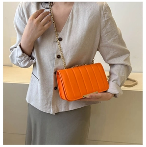 Detail of orange crossbody bag with gold chain strap and textured vertical stripes