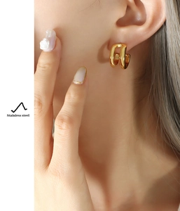 Detail shot of golden double-layer C-shaped stainless steel earrings on a model