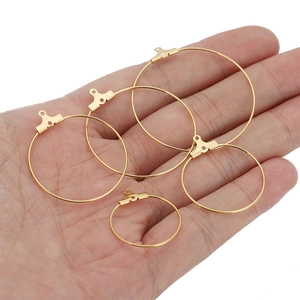 Four golden stainless steel round earring hoops for DIY jewelry making held in a palm