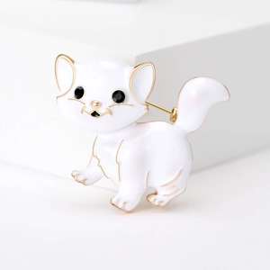 Detail of white enamel cat brooch with gold trim and black gemstone eyes on background