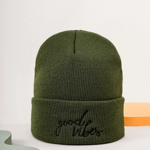 Army green knitted beanie with Good Vibes embroidery and cuffed design on a minimal setup