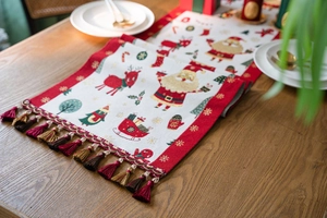 Detailed close-up of Christmas table runner with tassels, reindeer and Santa motifs