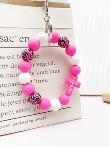 Close-up of pink leopard silicone beaded keychain with a Jesus cross pendant on a bag