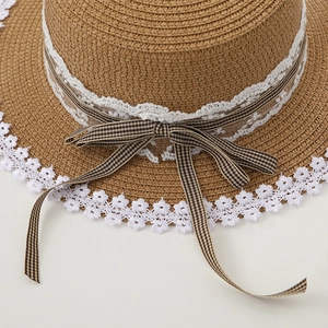 Detail of woven straw hat featuring white lace trim and checkered bow ribbon decoration