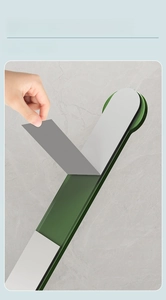 Detail showing hand peeling adhesive backing on green wall hook for easy installation