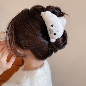 Detail of cute white plush animal hair claw clip worn on a woman's bun hairstyle