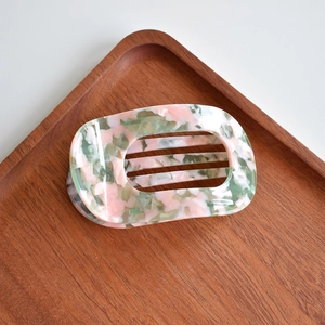 Macro detail of rectangular cutout acetate hair claw with pink and green marble texture