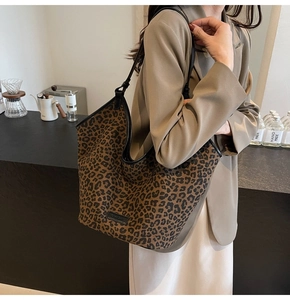 Detailed view of large leopard print tote bag with black straps on a blazer model