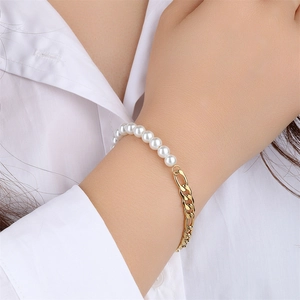 Close-up of golden Cuban chain and white pearl bracelet worn on a female wrist