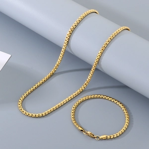 Detail of golden woven chain necklace and bracelet set with lobster clasp on grey stand