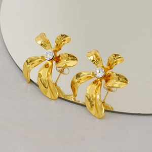 Exaggerated golden flower stud earrings with central crystal and brushed metal texture