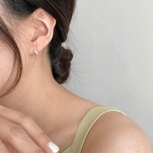 Close-up of minimalist silver teardrop stud earrings worn by a model in a side view