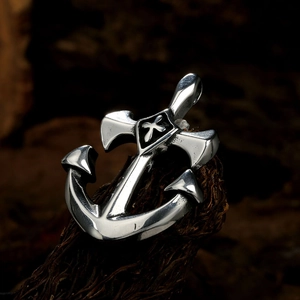 Detail of silver anchor and cross pendant with vintage finish on a rustic wood base