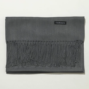 Detailed macro view of dark grey cashmere scarf texture with fringe and quality label