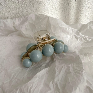 Détail de la pince à cheveux avec perles bleu gris et ressort en métal doré brillant