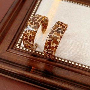 Macro detail of tortoiseshell acetate C-shaped earrings with polished resin finish