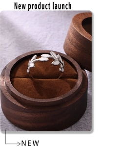 Close-up of olive leaf ring with white enamel detail in a wooden jewelry box